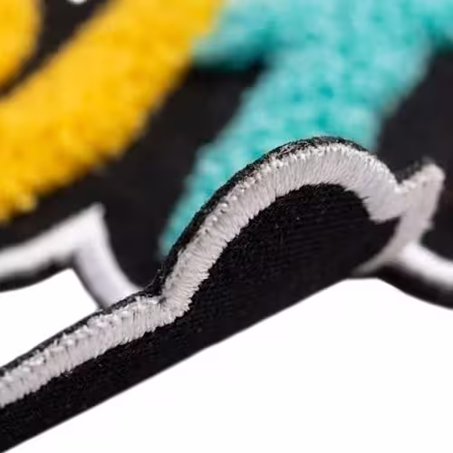 Close-up of a colorful chenille patch on black backing, highlighting a clean white stitched laser-cut border.