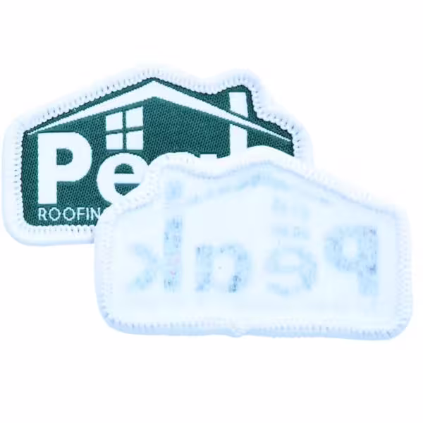 A house-shaped embroidered patch showing a plain, woven sew-on backing with reverse stitching.
