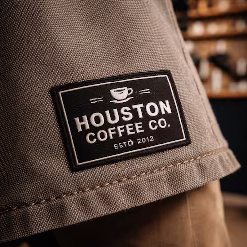 High-detail custom woven label patch on a heavy canvas barista apron.