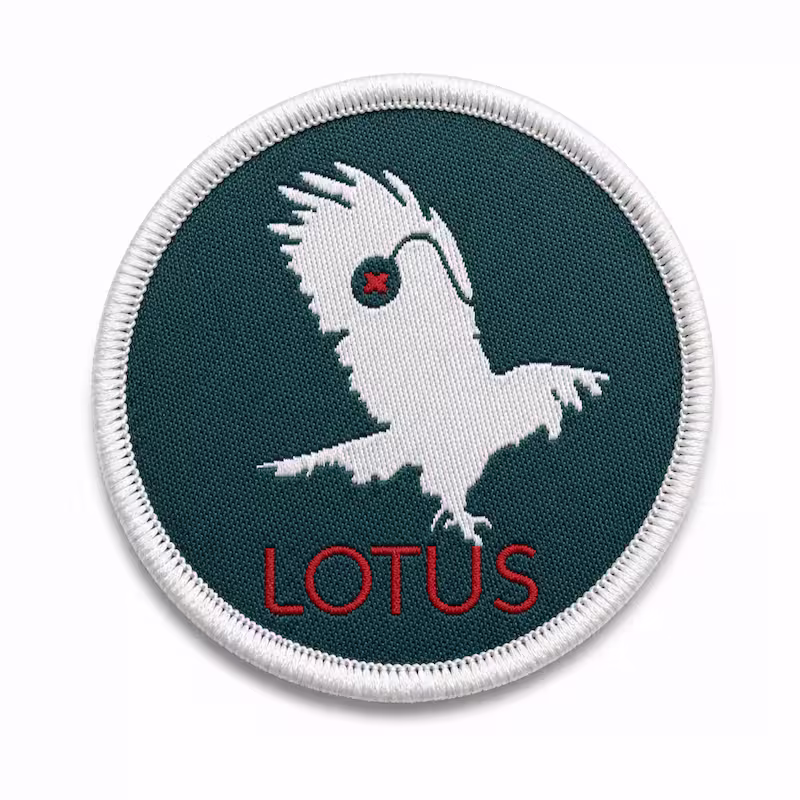 Circular dark green woven patch featuring a white diving bird silhouette a red X and LOTUS.