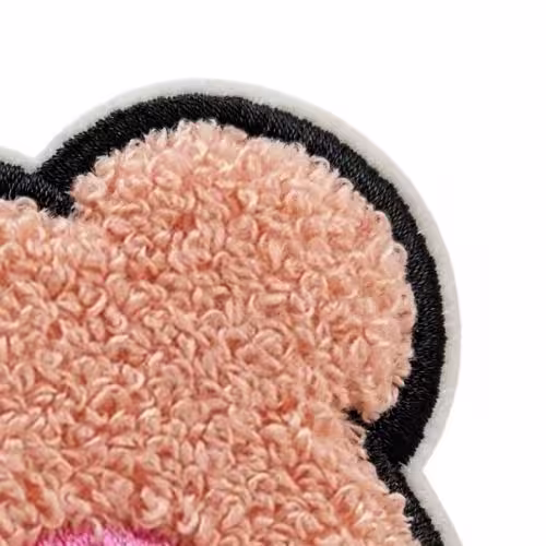 Close-up of a fluffy pink chenille patch featuring a thick black satin stitch border on white backing.