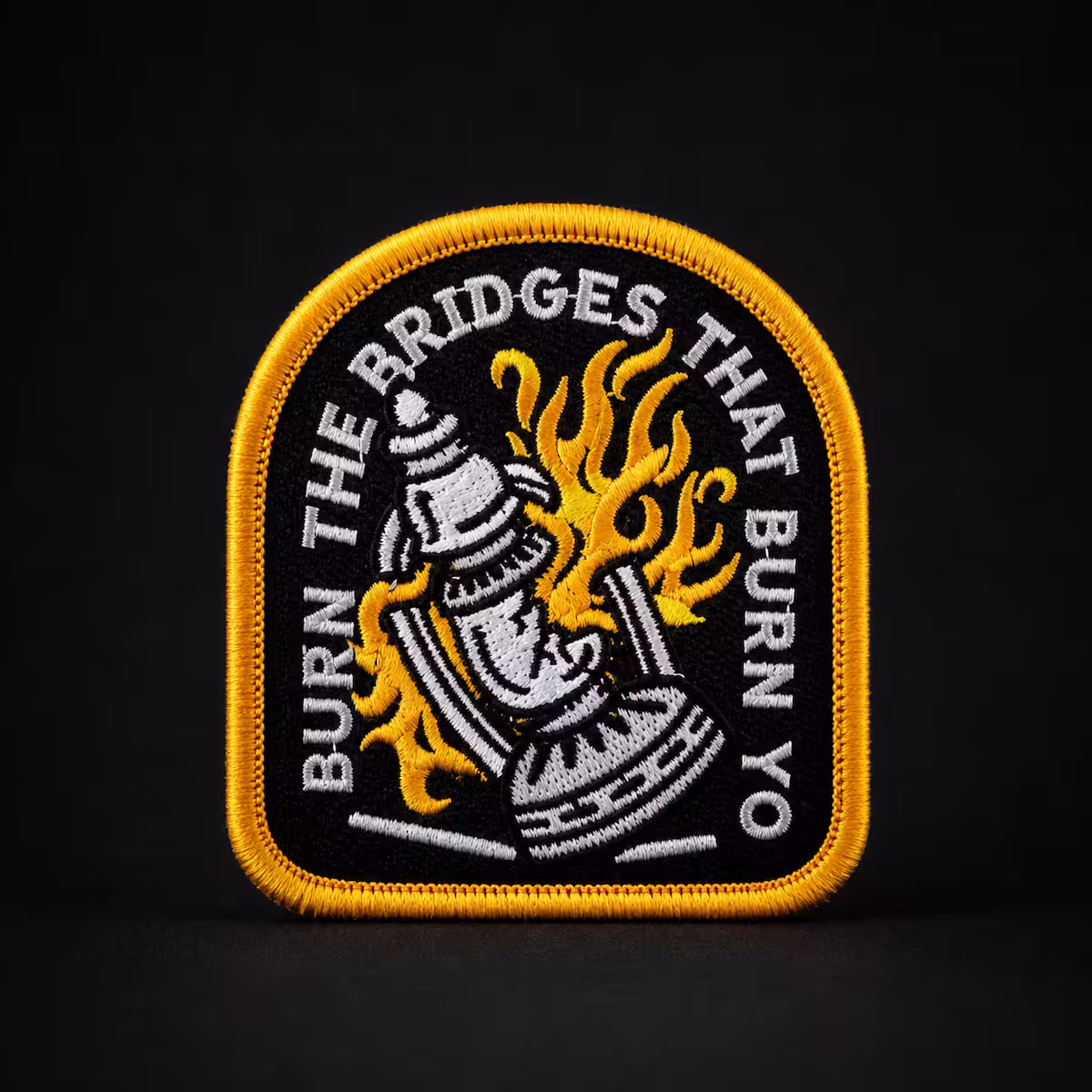 Black and yellow embroidered patch featuring a burning lantern and the text Burn The Bridges.