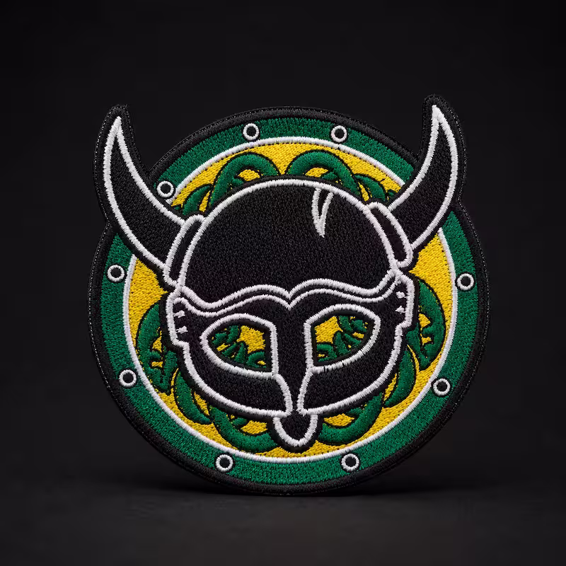 Circular embroidered patch showing a black horned Viking helmet over a green and yellow Celtic knot shield.